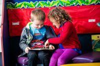 Two children seated sharing a book.